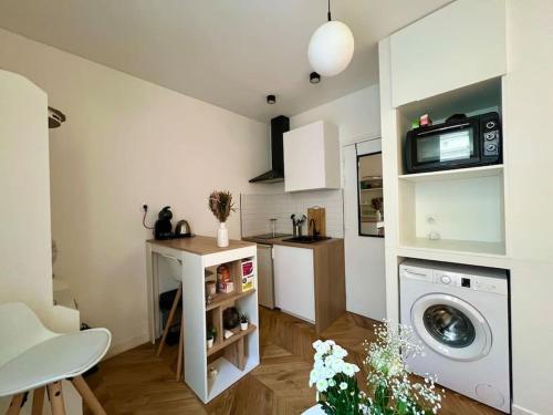 une petite cuisine avec un lave-linge et une table dans l'établissement Le Cosy Parisien - Au cœur du 13ème - 14MB, à Paris