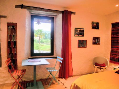 a bedroom with a window and a table and chairs at Les couleurs du Cagire in Estadens