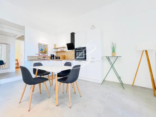 une cuisine blanche avec une table et des chaises dans l'établissement Le Voilier - Appartement Confortable Centre Cannes, à Cannes