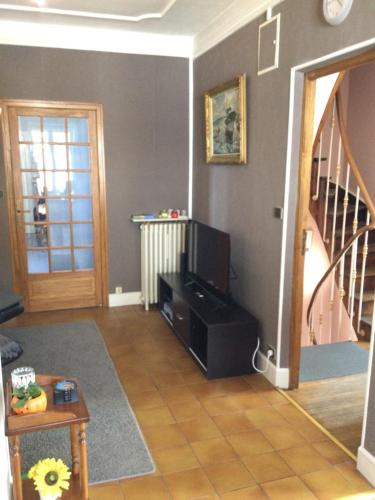 a living room with a television and a staircase at Couleur Framboise in Longwy