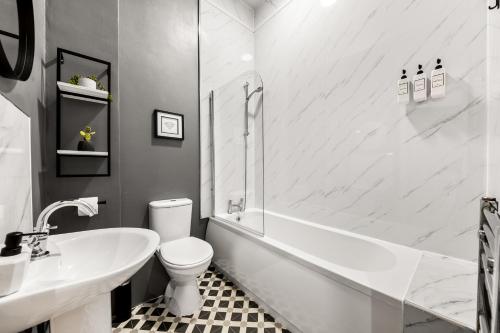 a bathroom with a tub and a toilet and a sink at Spacious Birmingham City Apartment in Birmingham