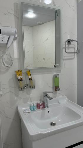 a white bathroom with a sink and a mirror at Mahbubakhon Guest house in old city in Bukhara