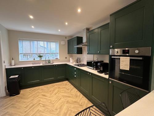 a green kitchen with green cabinets and a window at Durham Holiday Home in Durham