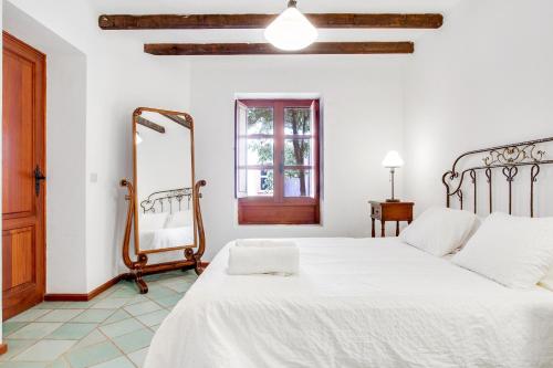 een witte slaapkamer met een bed en een spiegel bij Villa el Pescador in Yaiza