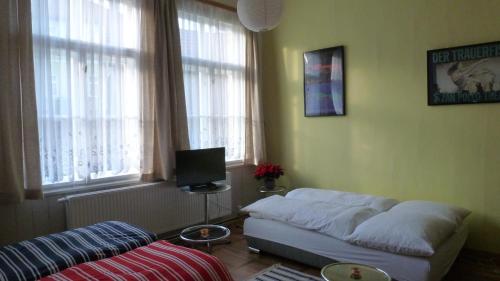 a living room with a bed and a tv and windows at Alte Schule in Tambach-Dietharz