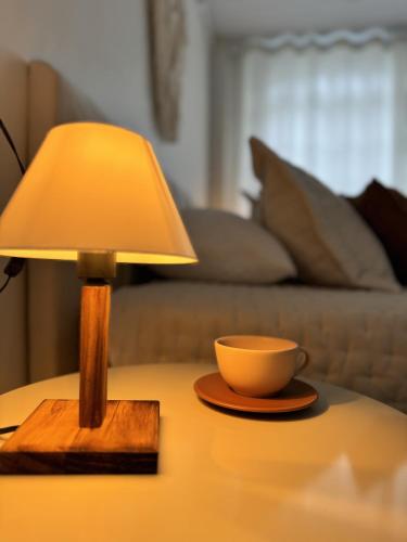a lamp on a table with a cup on it at Granbalaio Hostel in Blumenau