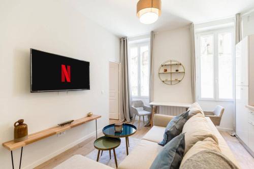 un salon avec un canapé et une télévision sur un mur dans l'établissement Cozy 1BR in the heart of Cours Julien | By Airnest, à Marseille