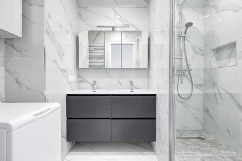 une salle de bain blanche avec un lavabo et une douche dans l'établissement Suite au Cœur de Paris, Architecturale et Élégante, à Paris