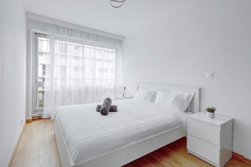 une chambre blanche avec un grand lit blanc et une fenêtre dans l'établissement Suite au Cœur de Paris, Architecturale et Élégante, à Paris