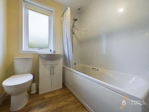 a bathroom with a toilet and a tub and a window at Dunard - Charming three bedroom cottage in Bigton in Sandwick