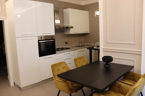 a kitchen with white cabinets and a black table and chairs at SUITE 38 in Campagnano di Roma