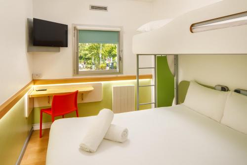 a bedroom with a bed and a desk with a computer at ibis budget Leicester in Leicester