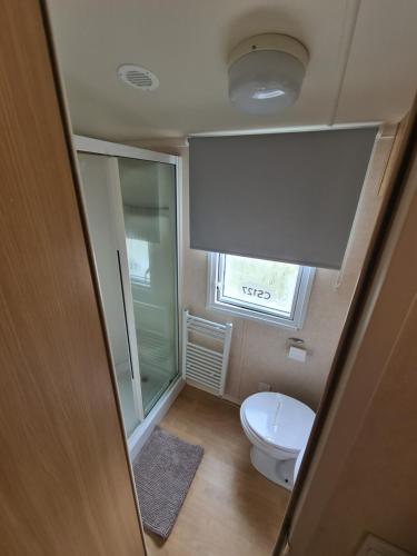 a small bathroom with a toilet and a window at 127cs HOBURNE NAISH HOLIDAY PARK in Highcliffe
