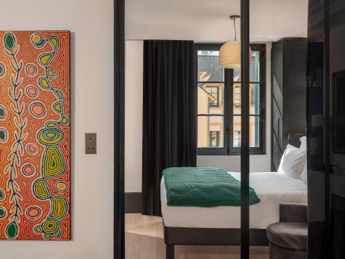 a hotel room with a bed and a painting on the wall at Balthazar Hotel & Spa Rennes - MGallery Collection in Rennes