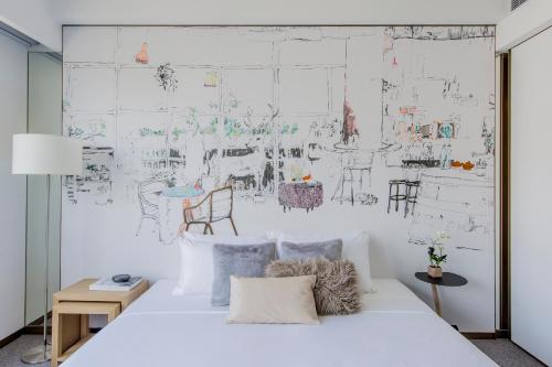 a bedroom with a white bed with drawings on the wall at Hotel Stage in Hong Kong