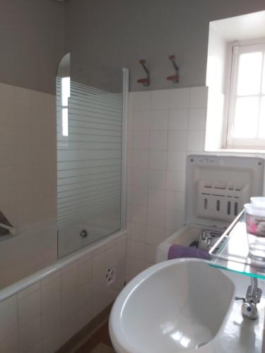 une salle de bain blanche avec un lavabo et une douche dans l'établissement Le capucin, à Le Mont-Dore