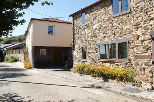 a stone building with a door and some flowers at O Bolaño Apt 2 in Parada de la Sierra