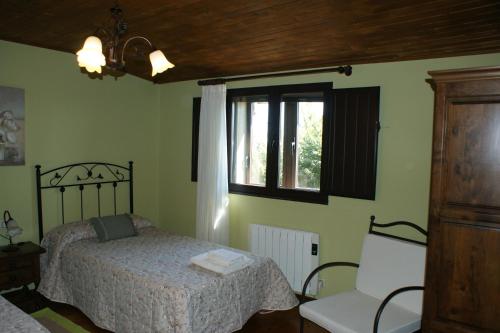 a bedroom with a bed and a window and a chair at O Bolaño Apt 2 in Parada de la Sierra