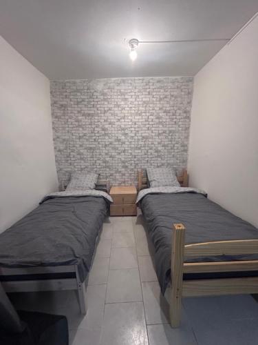 - 2 lits jumeaux dans une chambre avec un mur en briques dans l'établissement Appartement rez-de-chaussée, centre-ville, à Briatexte
