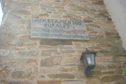 a sign on the side of a stone wall with a lamp at O Bolaño Apt 1 in Parada de la Sierra