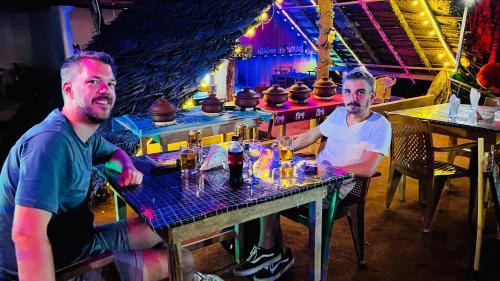 two men sitting at a table in a bar at Sigiriya Green Garden Home in Sigiriya