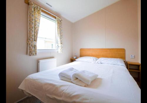 a bedroom with a white bed with towels on it at MP676 Parkdean Camber Sands in Camber