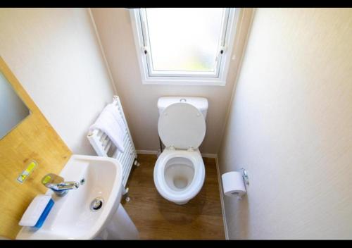 a bathroom with a toilet and a sink and a window at MP676 Parkdean Camber Sands in Camber