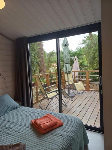 - une chambre avec un lit et une terrasse avec un parasol dans l'établissement Chalet la lande, à Ondres
