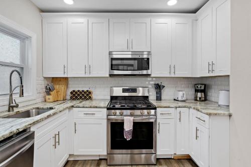 a kitchen with white cabinets and a stove and a sink at Beautifully Renovated 6BR 2BA 2 Blocks to Beach in Atlantic City