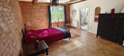 a bedroom with a red bed and a brick wall at Apartament nad morzem z podwórkiem in Będzino