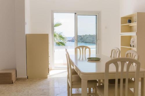 Un comedor con mesa y sillas y una ventana. en Coral Bay Beach House Apartment, en Peyia