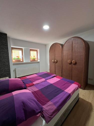 a bedroom with a bed with a purple and purple comforter at Apache Königswinter in Königswinter