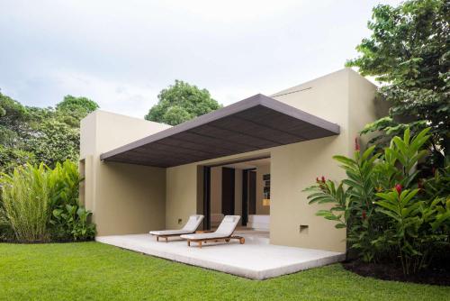 a house with two chairs and a porch with grass at w* Amazing 4BR Villa at Mesa de Yeguas in Anapoima