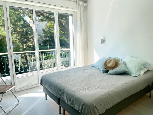 - un lit avec un chapeau dans une chambre dotée de fenêtres dans l'établissement Villa Topaze à La Baule, à Mazy