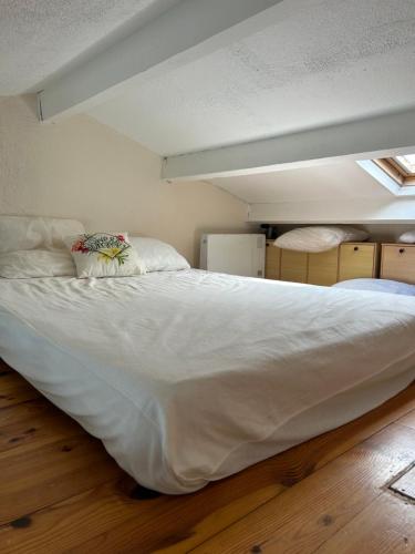 Cama blanca grande en habitación con suelo de madera en studio village naturiste, en Leucate