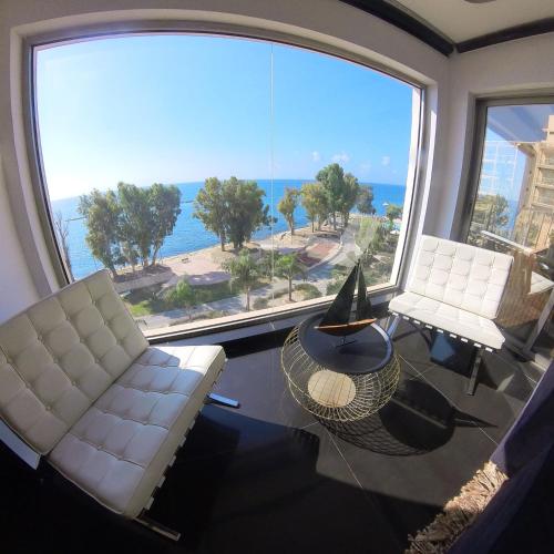 a living room with two white chairs and a large window at The View Beach Penthouse in Limassol