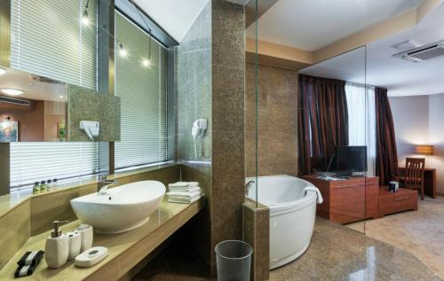 a bathroom with a tub and a sink and a toilet at Hotel Arka in Skopje