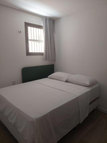 a bedroom with a large white bed with a window at Flecheiras in Trairi