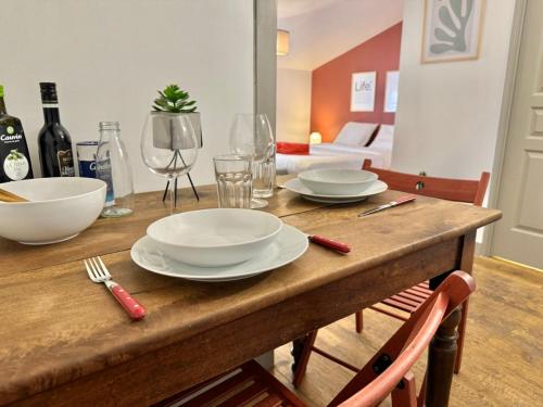 - une table en bois avec des assiettes, des verres et des bouteilles de vin dans l'établissement Studio OPERA - Place des Terreaux - Dreamy Flat Lyon, à Lyon