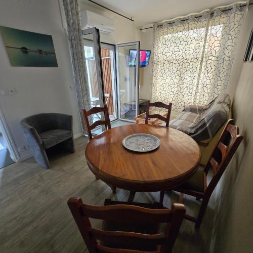 a living room with a table and a couch at T2 climatisé independant avec terrasse, garage à velos, centre arcachon à 3 minutes des plages et des rues pietones in Arcachon