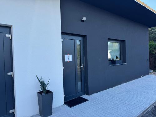 a building with a black door and a potted plant at j ONE Apartmány in Pardubice