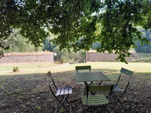 three chairs and a picnic table under a tree at Chalet charmant à Saint-Sylvestre avec Terrasse et Jardin in Ambazac
