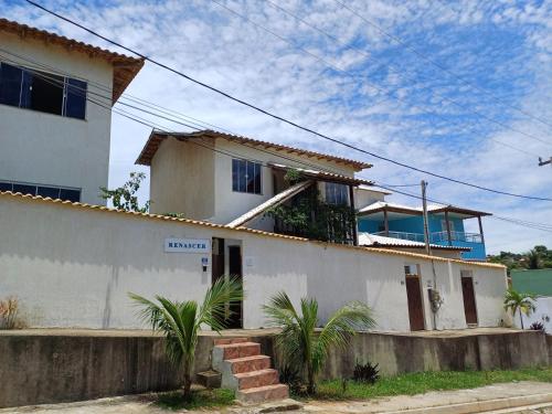 a white house with palm trees in front of it at Casa inteira con piscina compartilhada in Búzios
