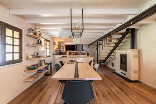 une grande cuisine avec une grande table et des chaises en bois dans l'établissement Chapelle de Léca, Authentique Chapelle Rénovée - Vallespir - Vue Imprenable Montagne - Unique, Loft Moderne et Pittoresque - WIFI - Confort Premium - OFFRE SPECIALE - Majestic Key Konciergerie Collioure, à Corsavy