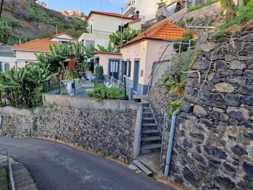 a stone wall and stairs next to a street at House in Camara de Lobos in Estreito de Câmara de Lobos