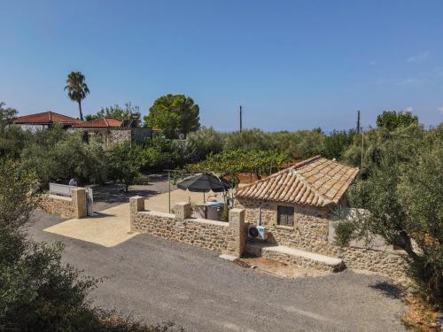 a stone building with an umbrella in a yard at olive grove by the sea 30m from the beach in Kardamili