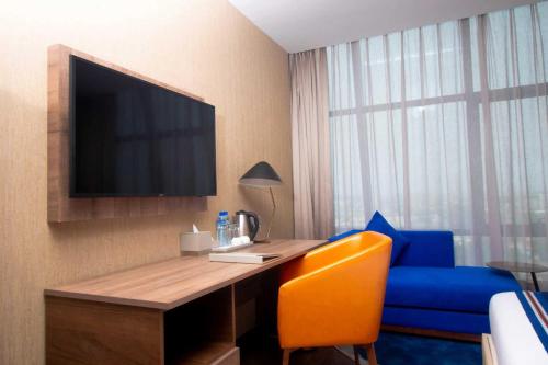 a hotel room with a desk with a tv and a blue chair at CIKA GOLDEN HOTEL and SUITES in Lomé
