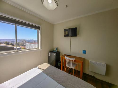 a bedroom with a bed and a desk and a window at Hostal Terraza Recreo in Viña del Mar