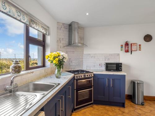 a kitchen with blue cabinets and a sink and a window at McDara Island View in Carna