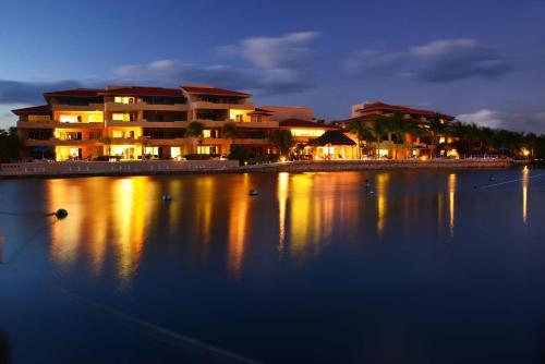 a group of buildings on the water at night at Portobello Gran Marina in Puerto Aventuras